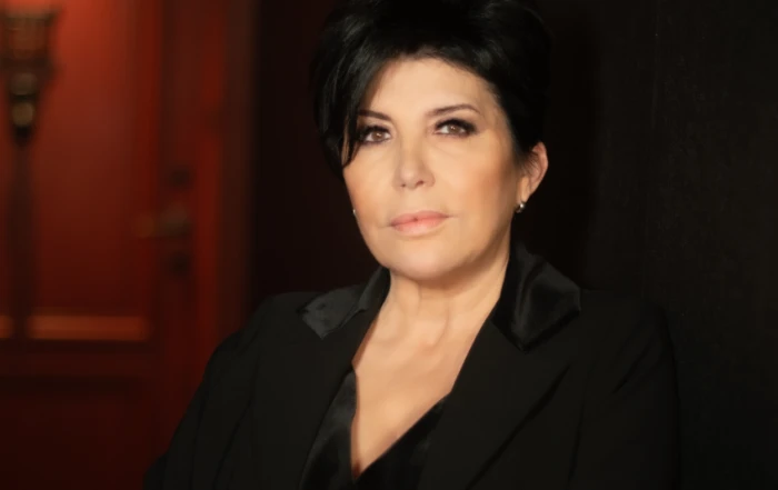 Portrait de la chanteuse Liane Foly vêtue d'une veste noire en velours, le regard posé vers l'objectif.